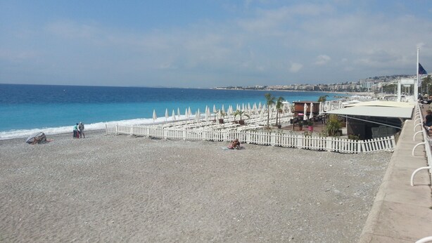 Una playa con sombrillas, una cerca y vistas al mar.