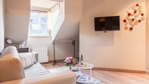 Ein modernes Wohnzimmer mit einer Couch, einem Couchtisch mit Getränken, einem Fernseher und einem dekorativen Wandbild.