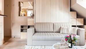 Ein modernes Wohnzimmer mit einer Couch, einem Couchtisch mit Blumenvase und einem Spiegel an der Wand.