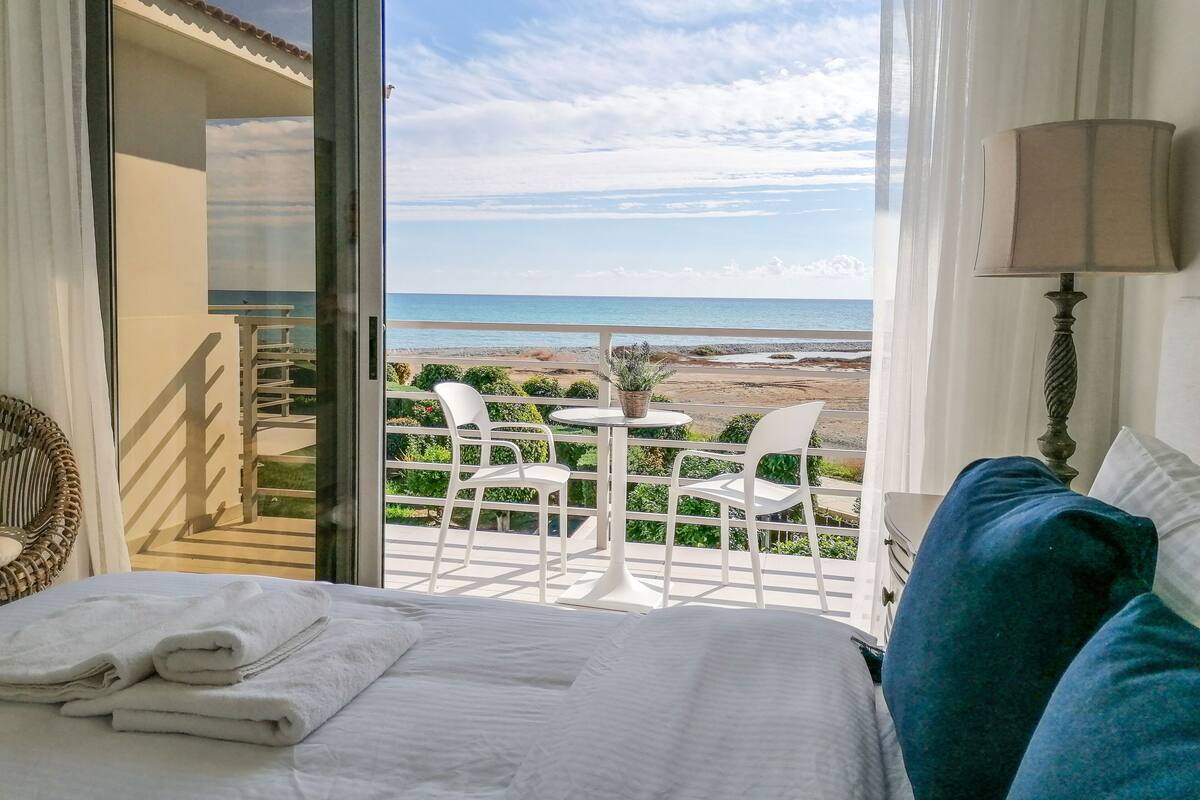 Ein Hotelzimmer mit Balkon und Blick auf einen Strand.
