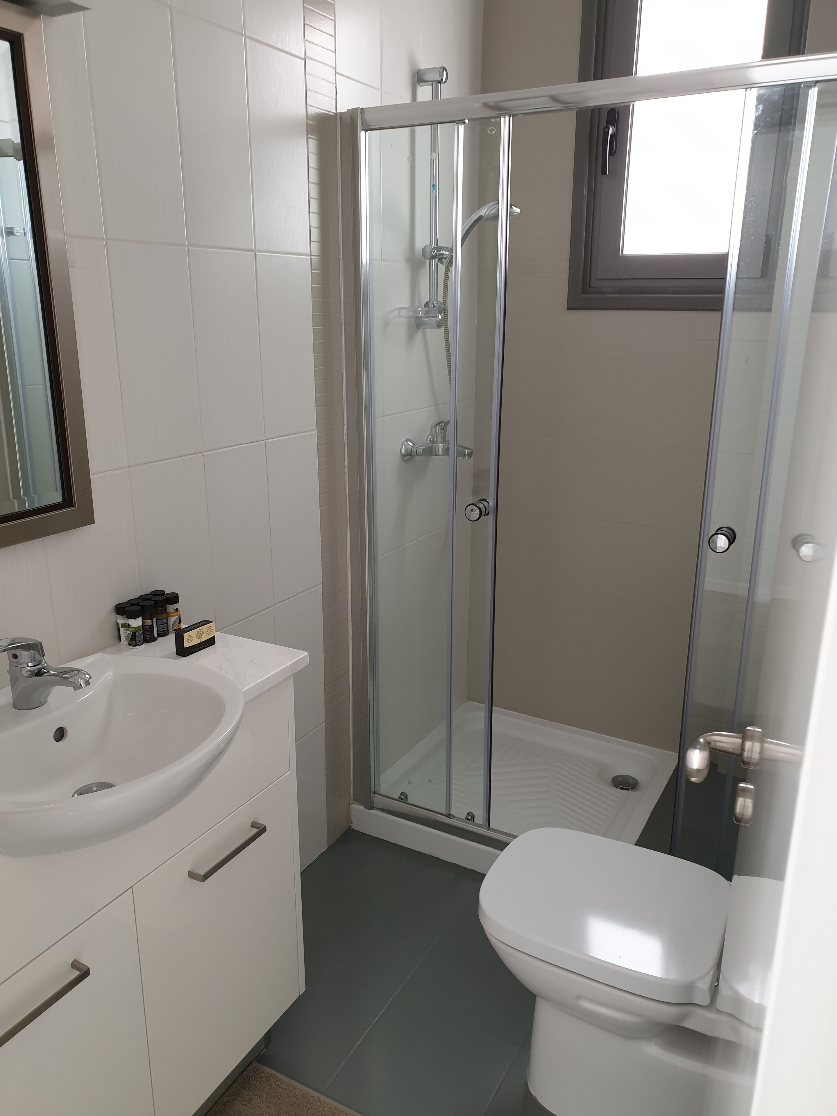 Een moderne badkamer met een douchecabine van glas, een witte wastafel en een toilet.