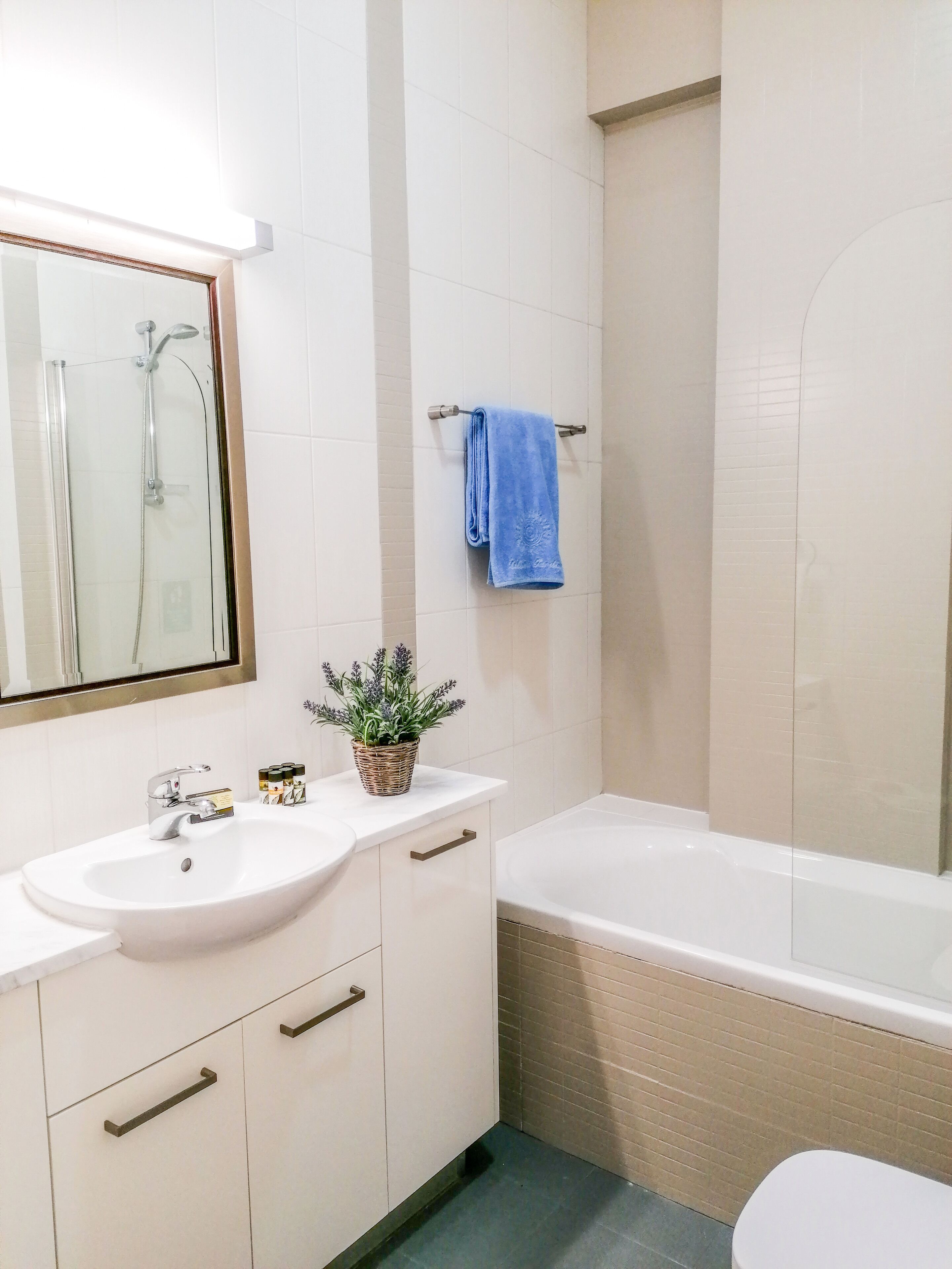 A bathroom with a white sink, mirror, and a bathtub.