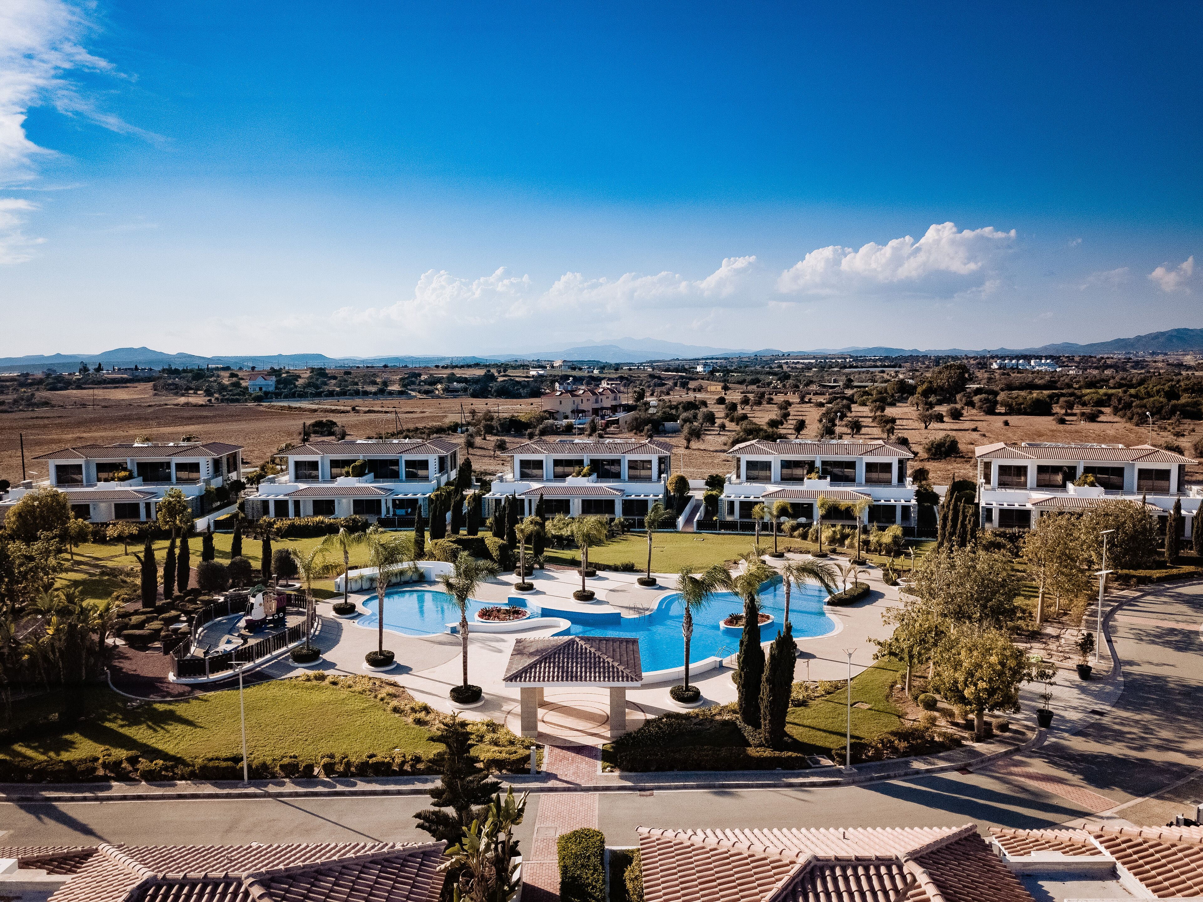 A resort with multiple villas, a central swimming pool, and landscaped gardens.