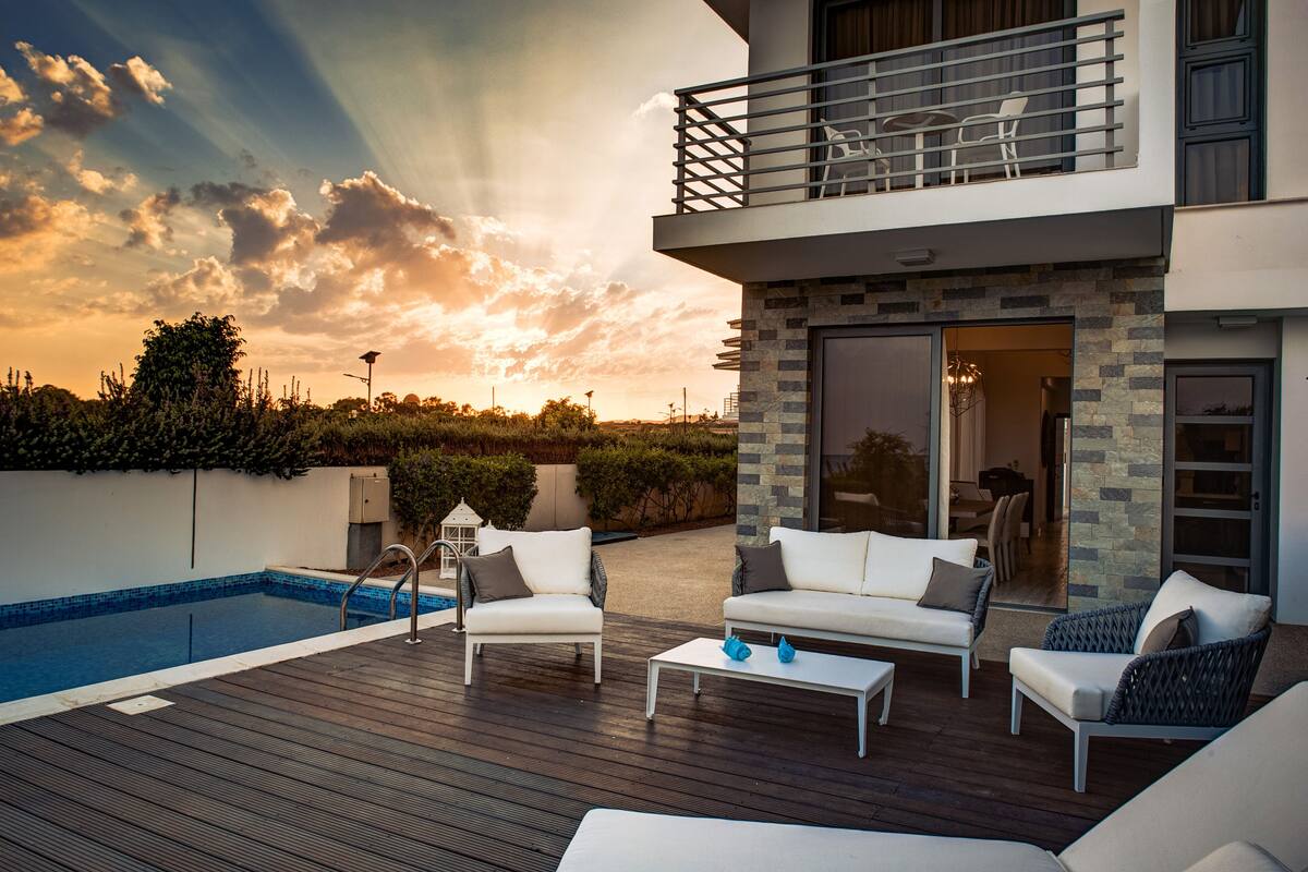 Eine moderne Außenterrasse mit Pool, weißen Sofas und einem Essbereich.