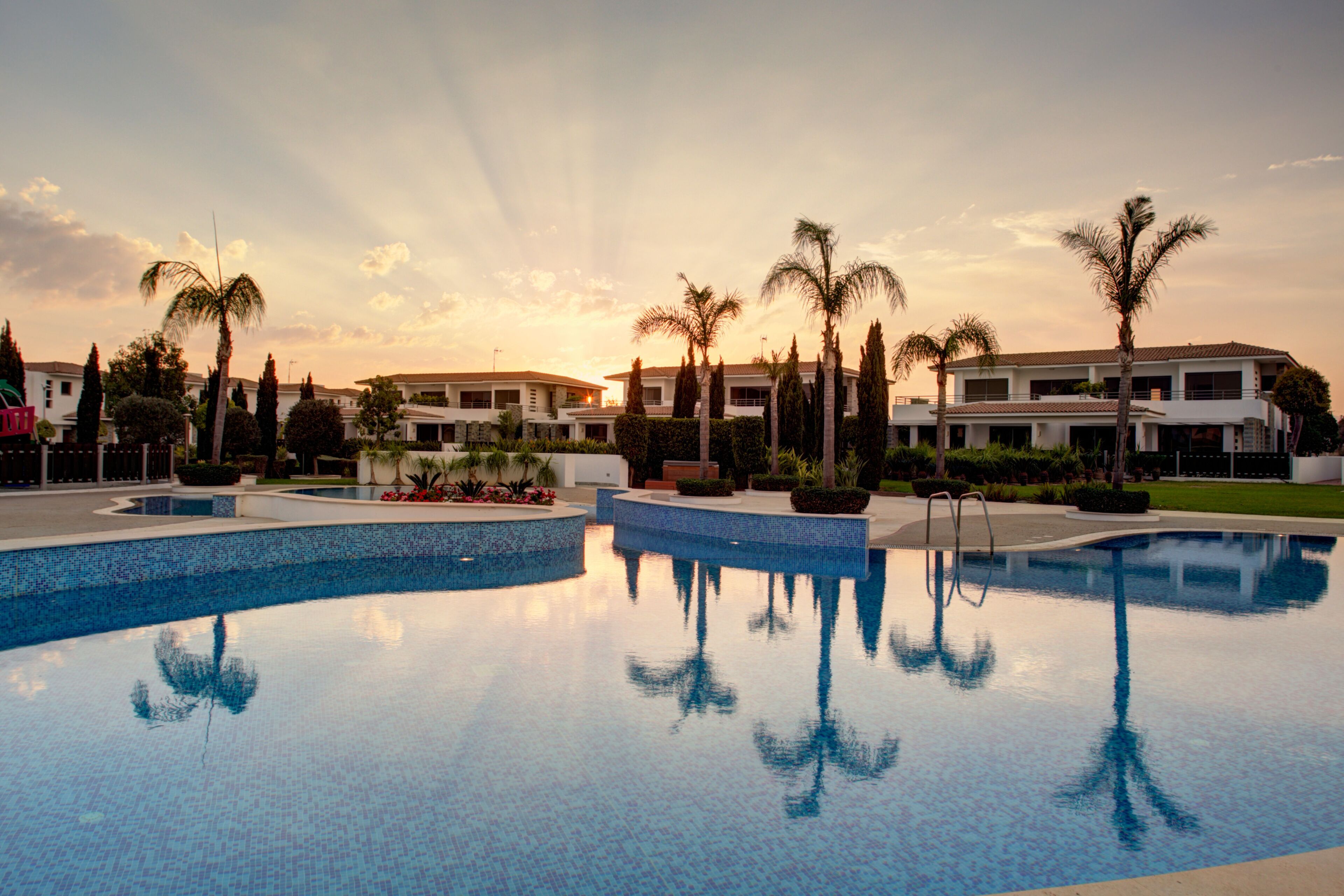 A swimming pool with a clear view of the surrounding buildings and palm trees.