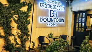 A hotel sign with a name in two languages, outdoor seating, and a small garden area. - Downtown Hotel Tbilisi (Tbilisi)