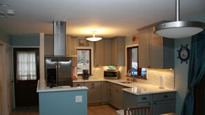 A compact kitchen with a refrigerator, microwave, and coffee maker. - Cleves Point Estates Home, Private sandy beach (Greenport)