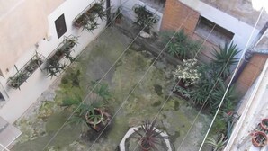 Une cour intérieure agrémentée de plantes en pot, d’une petite fontaine et d’un sol carrelé.