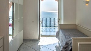 A balcony with a view of the sea, a bed, and a wardrobe.