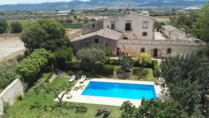Eine Villa mit Swimmingpool, umgeben von üppiger Vegetation und Blick auf die Landschaft.