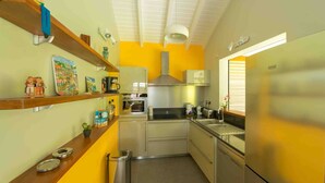 A compact kitchen with a microwave, stove, and a stainless steel refrigerator. - Treat yourself to a dream vacation! (Petit Bourg)