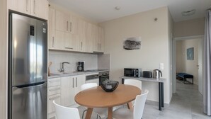 Eine moderne Küche mit Edelstahlgeräten, weißen Schränken und einem Esstisch aus Holz mit weißen Stühlen.