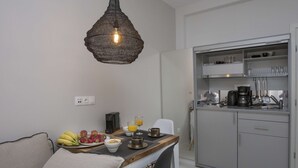 Une cuisine moderne avec des meubles gris, une table à manger où sont disposés des aliments pour le petit-déjeuner et un luminaire suspendu.
