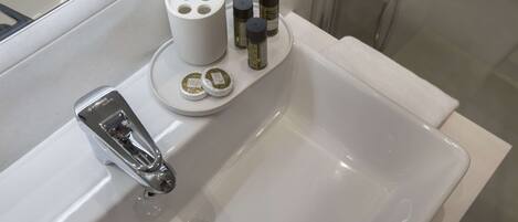 A bathroom sink with a chrome faucet, a soap dispenser, and two bottles of liquid soap on the edge.