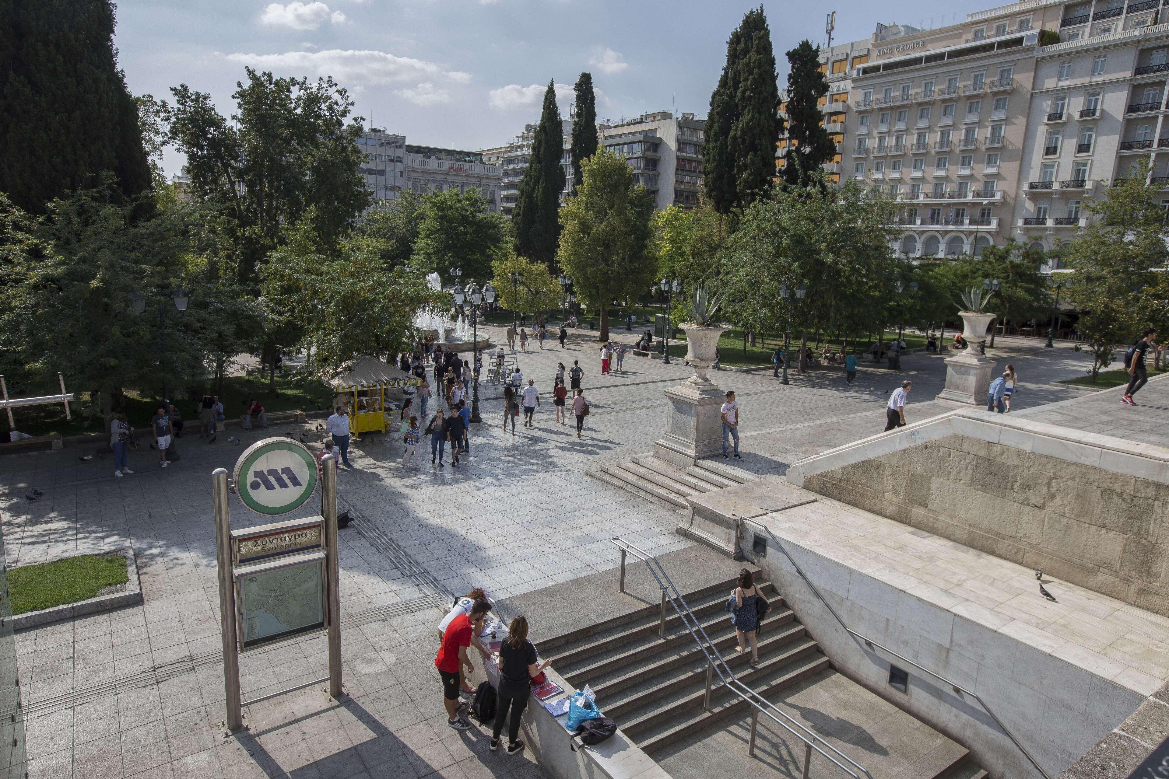 A public square with a fountain, benches, and a sign indicating a metro station.