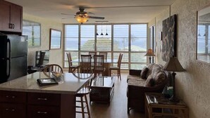 A spacious kitchen with a dining area, large windows, and a ceiling fan.