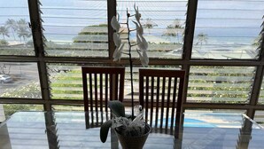 A dining area with a glass table, chairs, and a decorative plant.