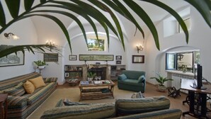 A spacious living room with a fireplace, a sofa, a green armchair, and a coffee table. - Casa Santacroce 2 with large garden (Praiano)