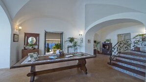 A spacious foyer with a wooden bench, a staircase with decorative railings, and a view of the outdoors. - Casa Santacroce 2 with large garden (Praiano)