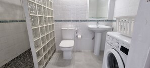 Ein Badezimmer mit Toilette, Waschbecken und Waschmaschine.