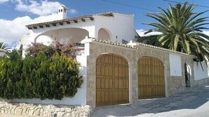 Un edificio bianco con base in pietra, porte in legno e una piccola torre.