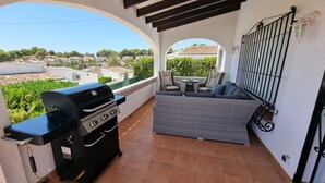 Un balcone con una griglia, posti a sedere all'aperto e vista sul quartiere.