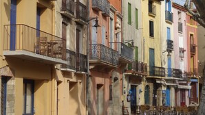 A row of colorful buildings with balconies, some with metal railings and others with ornate designs. - Collioure: beautiful apartment classified ***, quiet, swimming pool, garden, private parking (Collioure)
