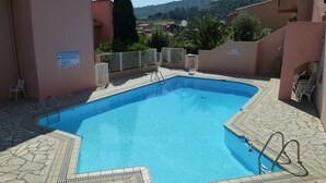 A rectangular swimming pool with a tiled deck, surrounded by a low wall and a metal fence. - Collioure: beautiful apartment classified ***, quiet, swimming pool, garden, private parking (Collioure)
