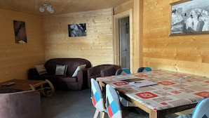 Une pièce chaleureuse avec un décor intérieur en bois, un canapé, une table à manger avec des chaises et un tableau accroché au mur.