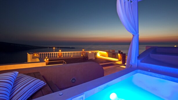 A rooftop lounge area with a pool, seating, and a view of the ocean at dusk. - Oia Mansion 4 Bedroom Villa With Panoramic Sunset View (Santorini)