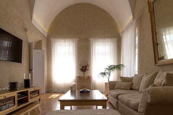 Una sala de estar con un techo alto en arco, un sofá, una mesa de centro y un televisor en la pared.