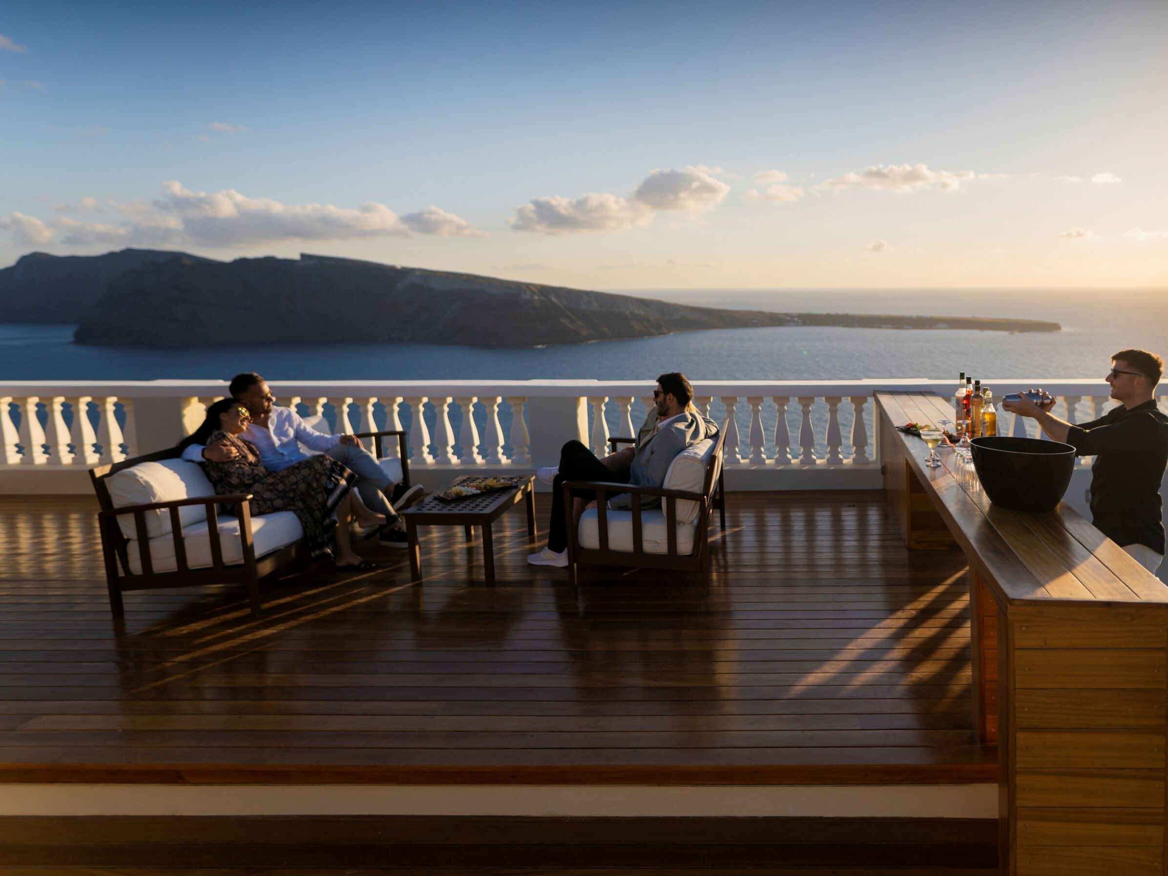 Eine Terrasse mit Sitzgelegenheiten und einer Bar mit Blick auf ein Gewässer.