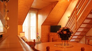 Un comedor acogedor de madera con una mesa redonda, sillas y un centro de mesa con flores.