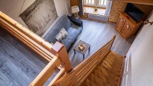 Una escalera de madera que conduce a una sala de estar con un sofá y una mesita.
