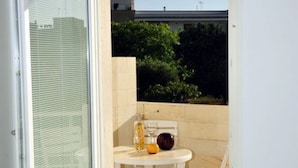 A small balcony with a white table, a chair, and a glass of orange juice. - App. PORTO RUSSO♡ Splendid studio apartment (Otranto)