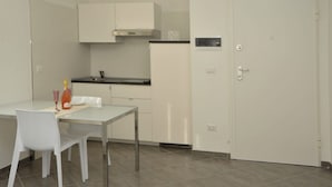 A small, modern kitchen with white cabinets, a countertop, and a door. - App. PORTO RUSSO♡ Splendid studio apartment (Otranto)