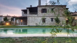 A stone house with a pool, surrounded by greenery and a sunset in the background. - Luxurious Stone House in Elani (ΑΜΑ : 00000239911) (Siviri, Chalkidiki)