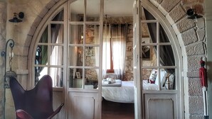 A rustic room with a stone wall, a bed with white bedding, and a chair. - Luxurious Stone House in Elani (ΑΜΑ : 00000239911) (Siviri, Chalkidiki)
