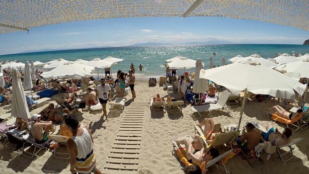 A beach with sun loungers and umbrellas, a wooden walkway, and a clear view of the sea. - Luxurious Stone House in Elani (ΑΜΑ : 00000239911) (Siviri, Chalkidiki)