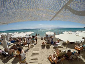 A beach with sun loungers and umbrellas, a wooden walkway, and a clear view of the sea. - Luxurious Stone House in Elani (ΑΜΑ : 00000239911) (Siviri, Chalkidiki)