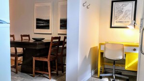 Cozinha compacta com mesa de jantar, cadeiras, escrivaninha amarela e mapa emoldurado de Quebec.