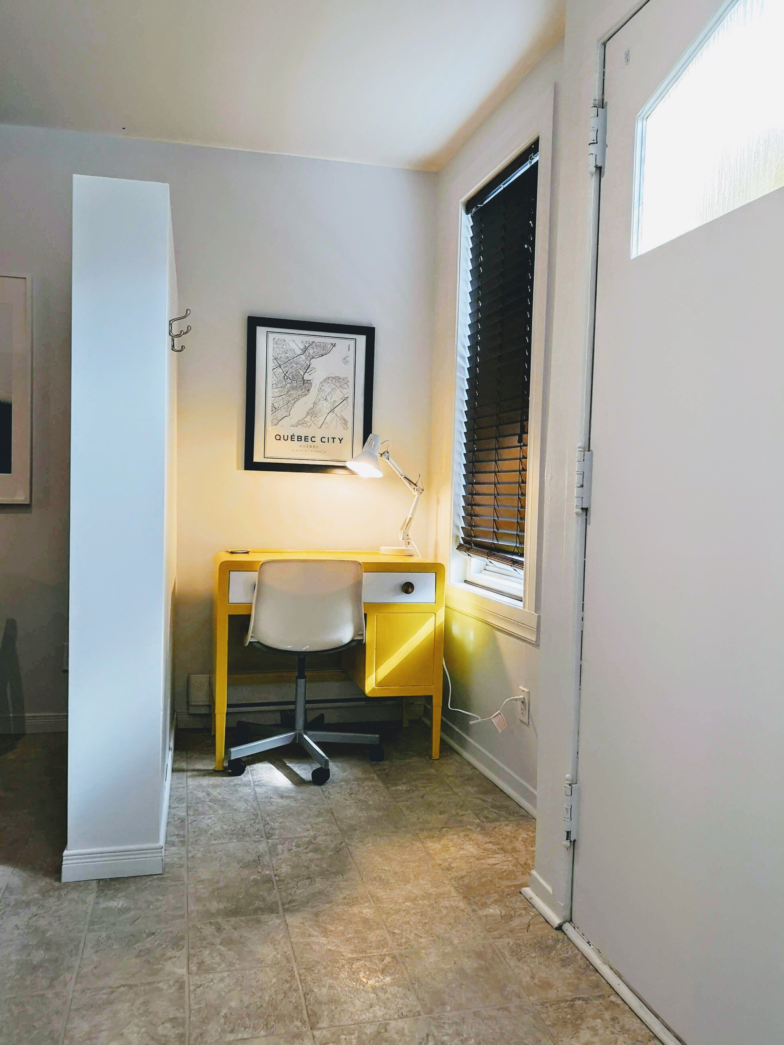 A small office space with a desk, chair, and a framed map of Québec City on the wall.