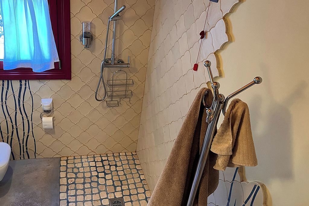 Een badkamer met een douche, een handdoekrek en een vloer met een patroon.