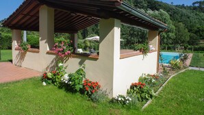 A covered outdoor seating area with a pool in the background. - CASALE LA FATA, SMEMORINA splendid apartment facing the pool, sleeps 5 (camaiore)