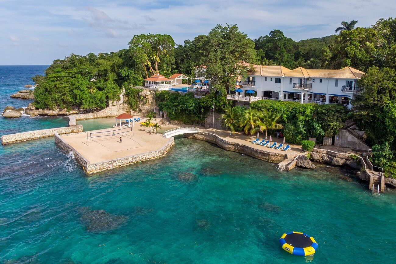 A coastal property with a swimming pool, a bridge, and a beach area.