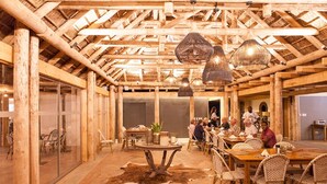 An indoor dining area with wooden beams, wicker furniture, and hanging light fixtures. - Norotshama River Resort (Aussenkehr)