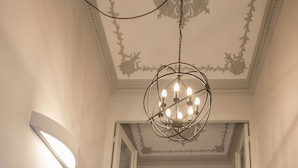 Un couloir agrémenté d’un lustre, d’une applique murale et d’une porte ornée de moulures décoratives.