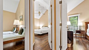 Ein Schlafzimmer mit zwei Betten, einem Deckenventilator und einem Fenster mit Jalousien.
