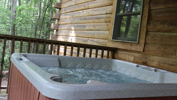 Une cabane en bois avec un jacuzzi sur la véranda.