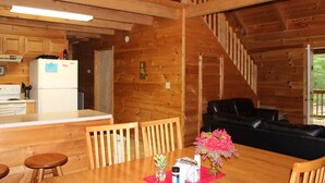 L’intérieur d’un chalet en bois comprend une cuisine, un coin repas et un canapé en cuir noir.